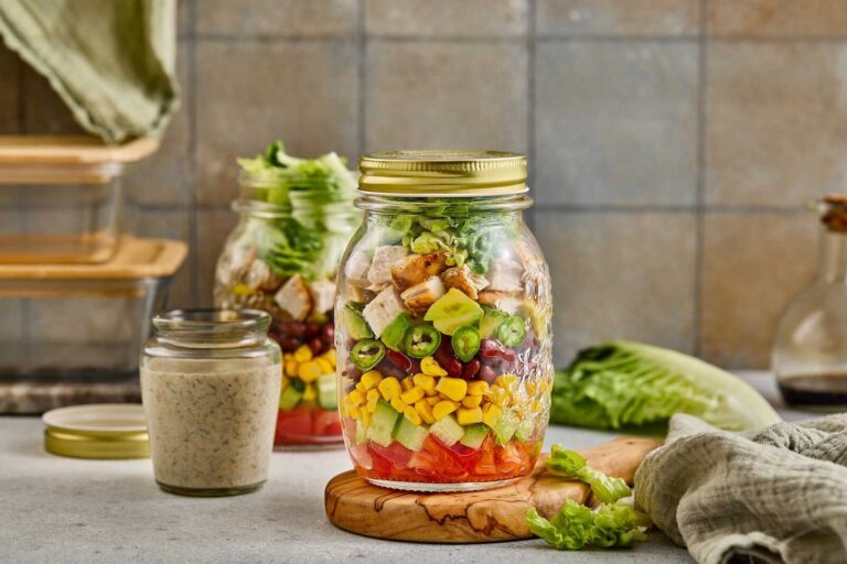 Southwest chicken salad layered in a mason jar with grilled chicken, corn, black beans, avocado, and romaine lettuce.