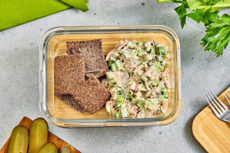 Tuna salad with celery and flaxseed crackers in a glass meal prep container.